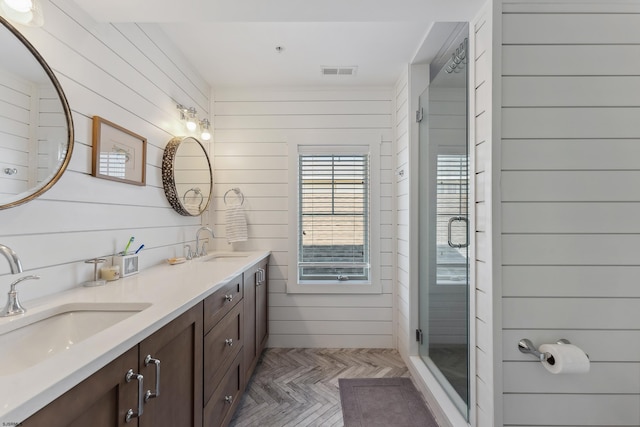 bathroom featuring parquet flooring, vanity, a shower with door, and wooden walls