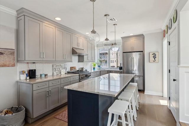 kitchen featuring decorative light fixtures, a center island, stainless steel appliances, and gray cabinets