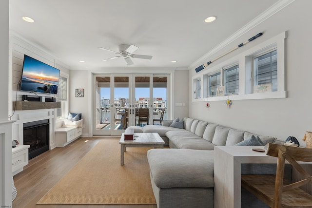 living room with ceiling fan, french doors, crown molding, and light hardwood / wood-style floors