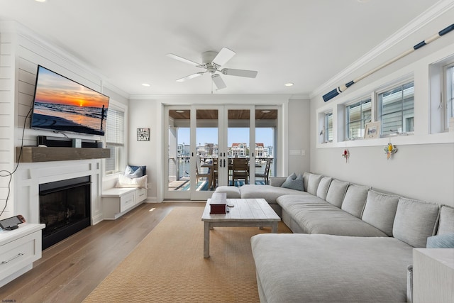 living room with ceiling fan, a wealth of natural light, light hardwood / wood-style flooring, and ornamental molding