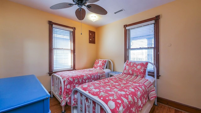 bedroom featuring ceiling fan, electric panel, and wood-type flooring