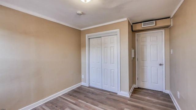 unfurnished bedroom with a closet, crown molding, and wood-type flooring