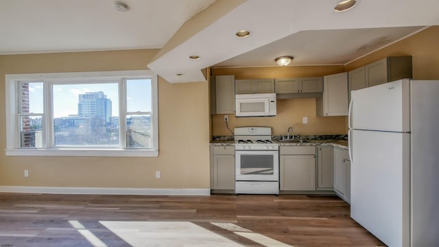 kitchen featuring dark hardwood / wood-style flooring, plenty of natural light, white appliances, and dark stone countertops