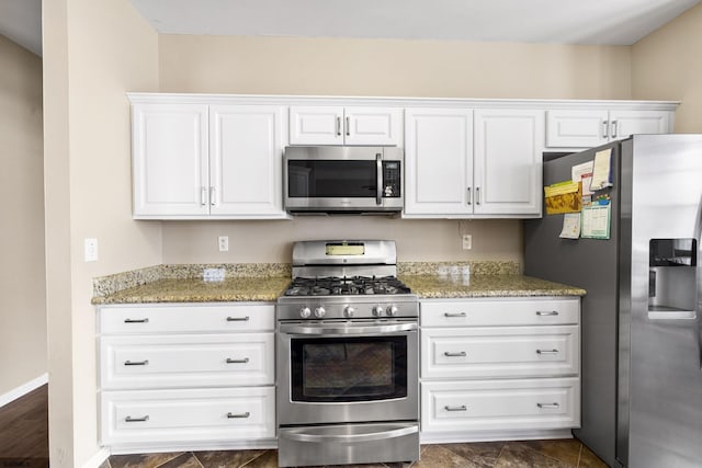 kitchen with stainless steel appliances, white cabinets, and light stone counters