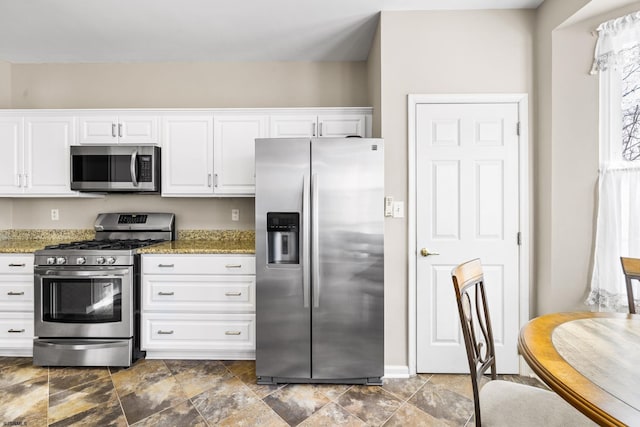 kitchen featuring appliances with stainless steel finishes, stone countertops, and white cabinetry