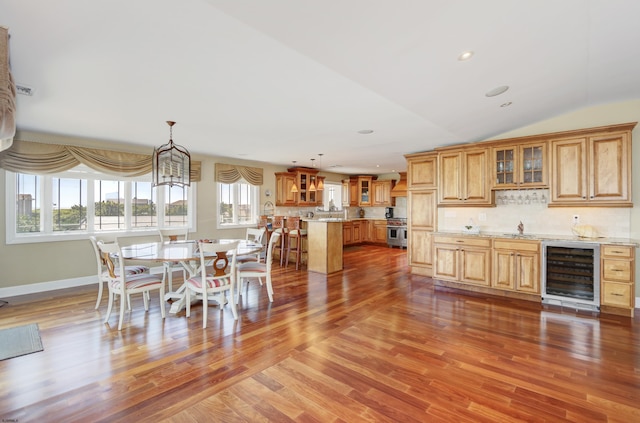 dining space featuring wine cooler, vaulted ceiling, and hardwood / wood-style floors