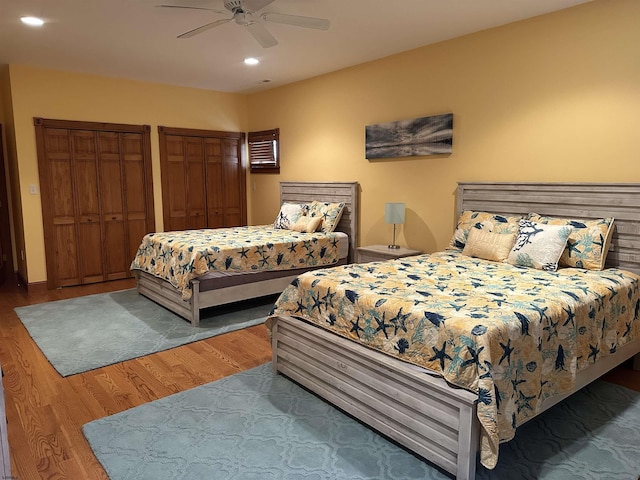 bedroom featuring ceiling fan, two closets, and wood-type flooring