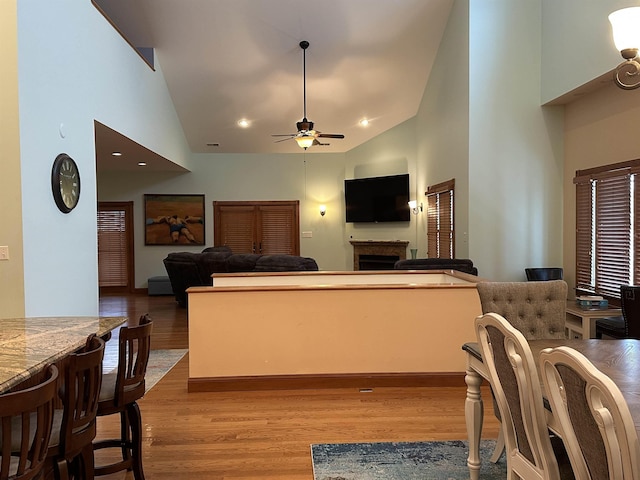 living room with ceiling fan, light hardwood / wood-style flooring, and high vaulted ceiling