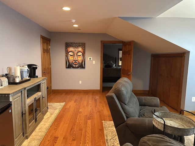 living room featuring vaulted ceiling and light hardwood / wood-style flooring