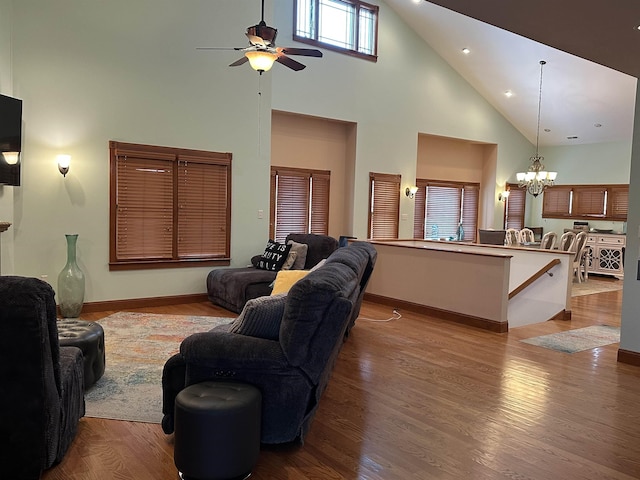 living room featuring ceiling fan with notable chandelier, light hardwood / wood-style floors, and a towering ceiling