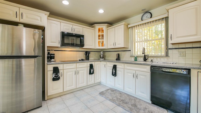 kitchen featuring light tile patterned flooring, sink, light stone counters, and black appliances