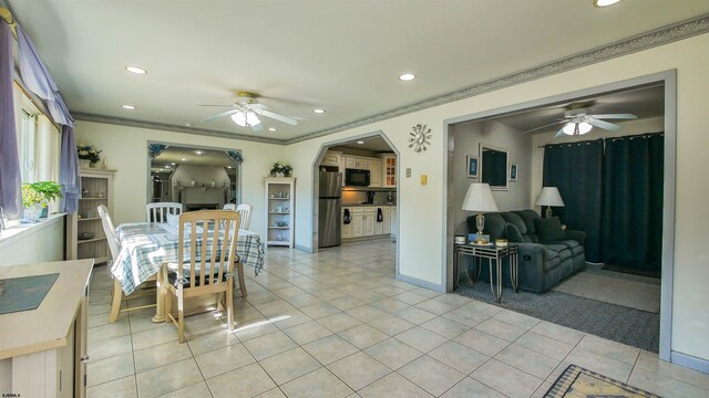 dining space with ceiling fan, light tile patterned floors, and ornamental molding