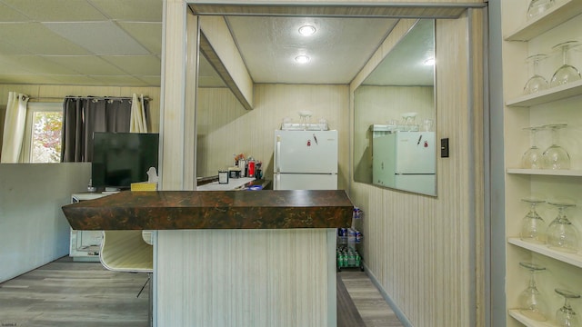 kitchen featuring wood-type flooring, built in shelves, wood walls, and white fridge