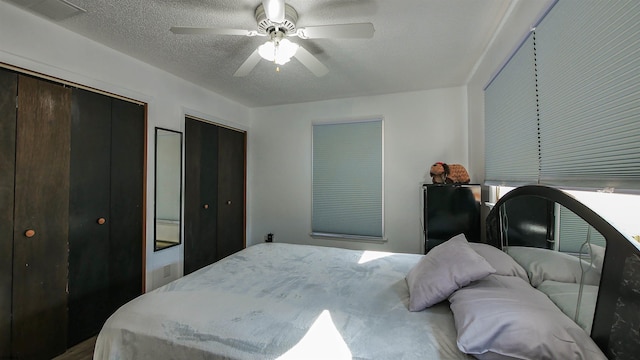 bedroom featuring a textured ceiling, multiple closets, and ceiling fan