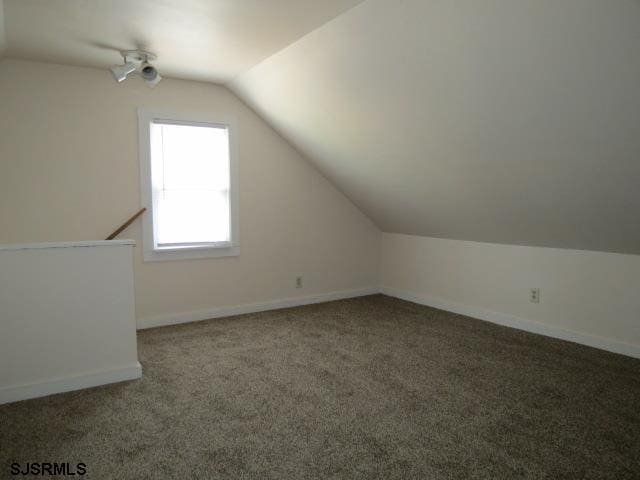 bonus room featuring vaulted ceiling and dark carpet