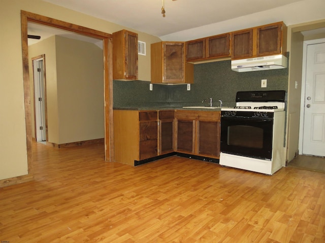 kitchen featuring tasteful backsplash, sink, range with gas stovetop, and light hardwood / wood-style floors