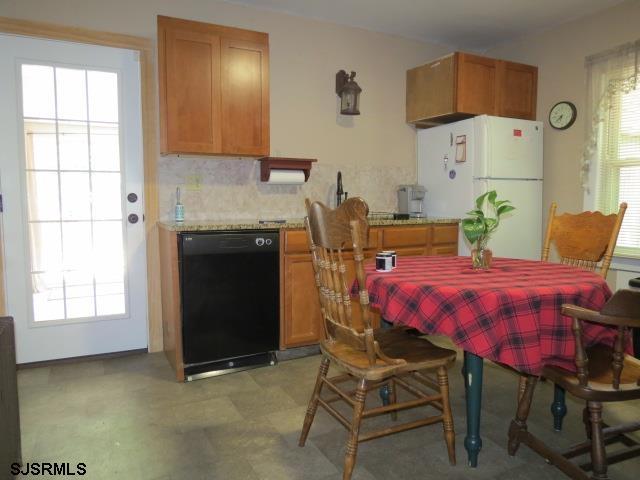 kitchen featuring white fridge, black dishwasher, and light stone countertops