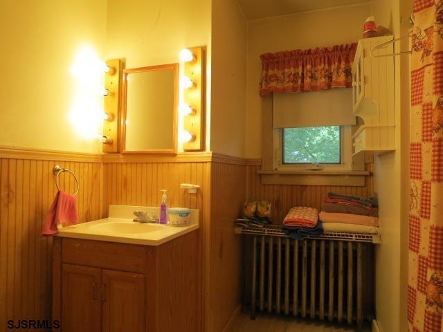 bathroom with curtained shower, radiator, and vanity