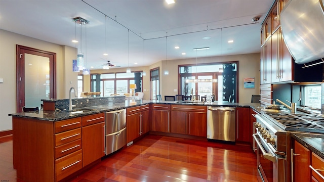 kitchen featuring ceiling fan, appliances with stainless steel finishes, dark stone counters, hanging light fixtures, and sink