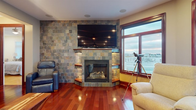 living area featuring hardwood / wood-style flooring, ceiling fan, and a fireplace