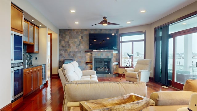 living room with ceiling fan, dark wood-type flooring, beverage cooler, and a fireplace