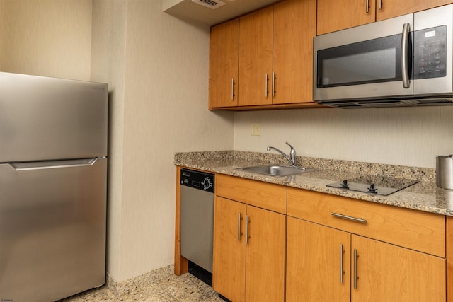 kitchen featuring light stone countertops, stainless steel appliances, and sink