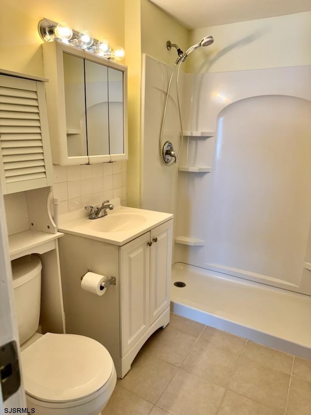 full bathroom featuring a shower, toilet, tile patterned floors, vanity, and backsplash