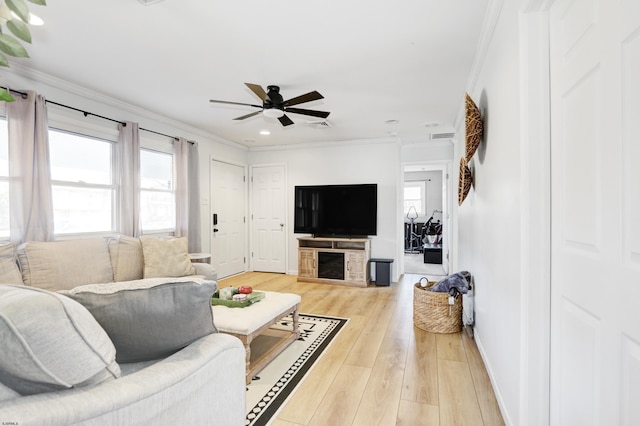 living room featuring ceiling fan, a wealth of natural light, light hardwood / wood-style flooring, and a fireplace