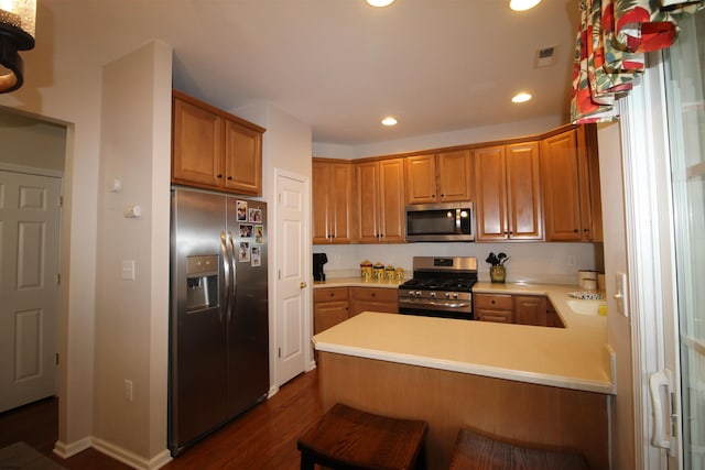 kitchen with stainless steel appliances, dark wood-type flooring, a breakfast bar area, and kitchen peninsula