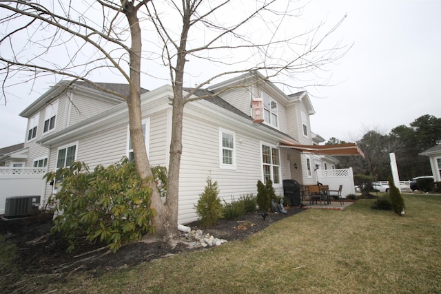 view of side of property featuring a patio area, central air condition unit, and a lawn