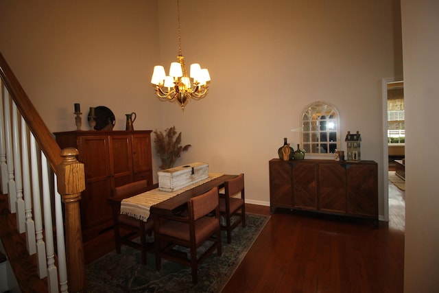 dining space with dark wood-type flooring, a towering ceiling, and a chandelier