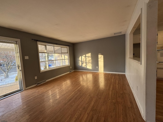 empty room with wood-type flooring and a healthy amount of sunlight