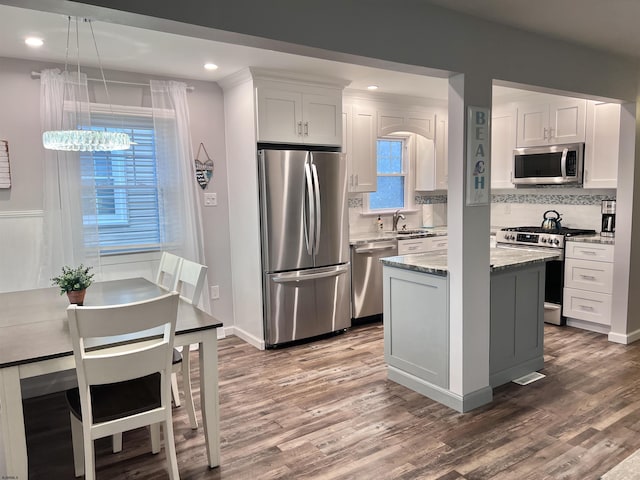 kitchen featuring a center island, sink, appliances with stainless steel finishes, white cabinets, and light stone counters