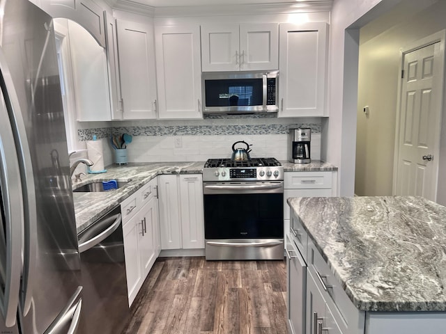 kitchen featuring stainless steel appliances, backsplash, white cabinets, and light stone countertops