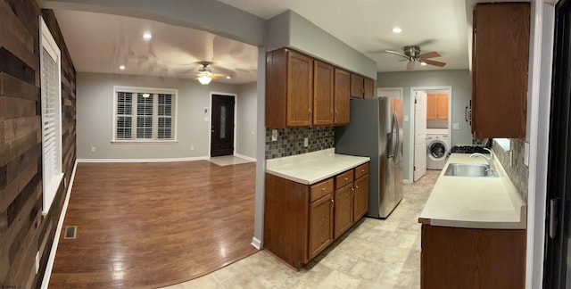 kitchen with washer / dryer, sink, backsplash, ceiling fan, and stainless steel fridge with ice dispenser