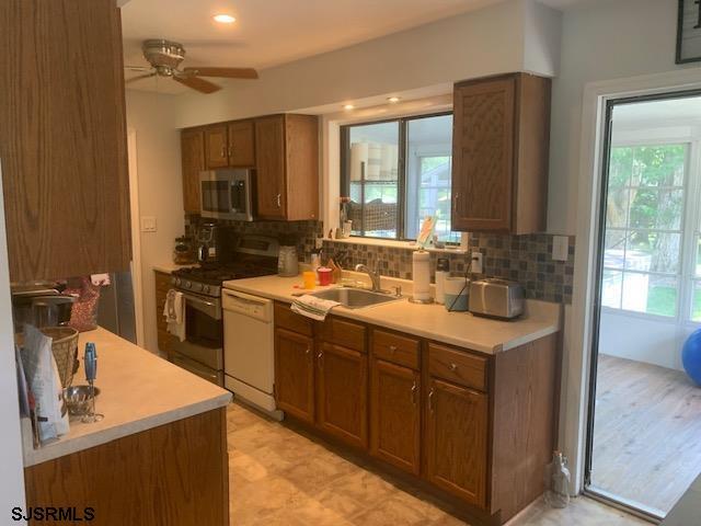 kitchen with range, decorative backsplash, sink, ceiling fan, and white dishwasher