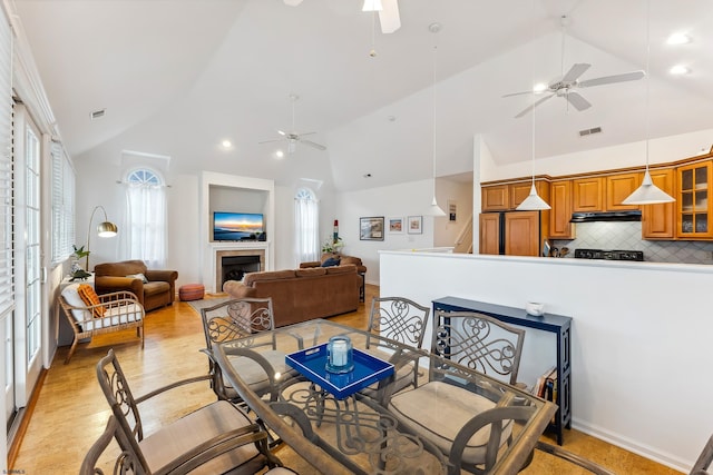 dining space featuring ceiling fan, light hardwood / wood-style flooring, and high vaulted ceiling