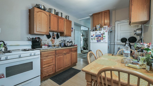 kitchen featuring sink, white appliances, and light hardwood / wood-style floors