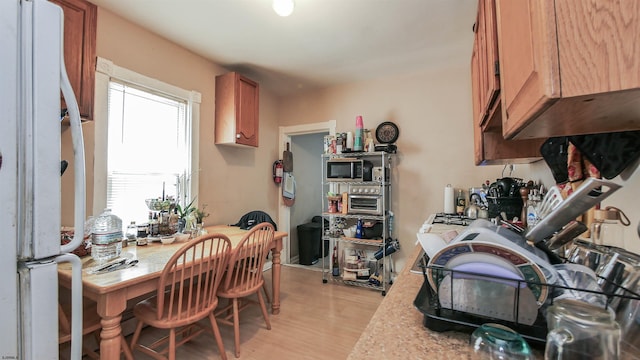 kitchen with a wealth of natural light, white refrigerator, and light hardwood / wood-style flooring