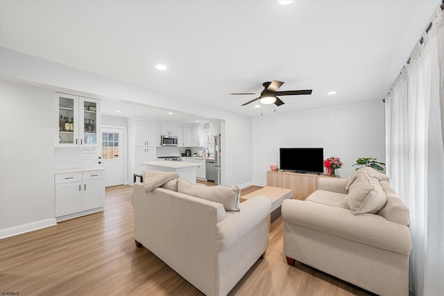 living room featuring light hardwood / wood-style floors, sink, and ceiling fan