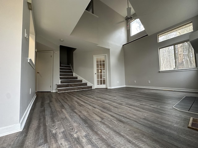 unfurnished living room featuring dark hardwood / wood-style floors, a towering ceiling, and ceiling fan