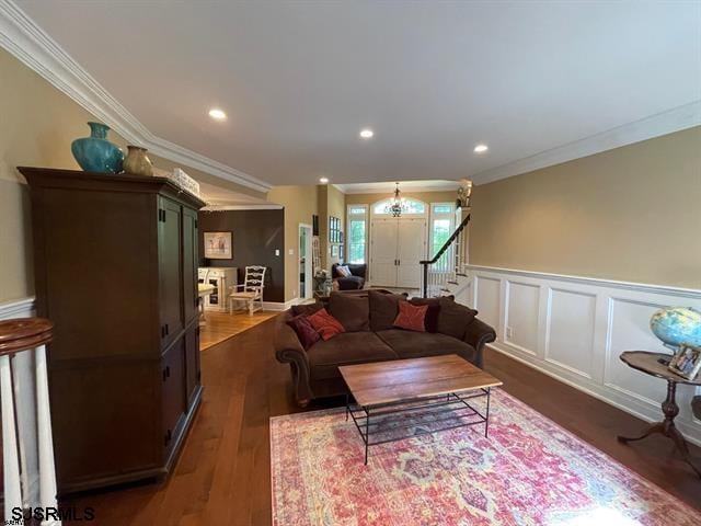 living room with dark hardwood / wood-style flooring, a notable chandelier, and ornamental molding