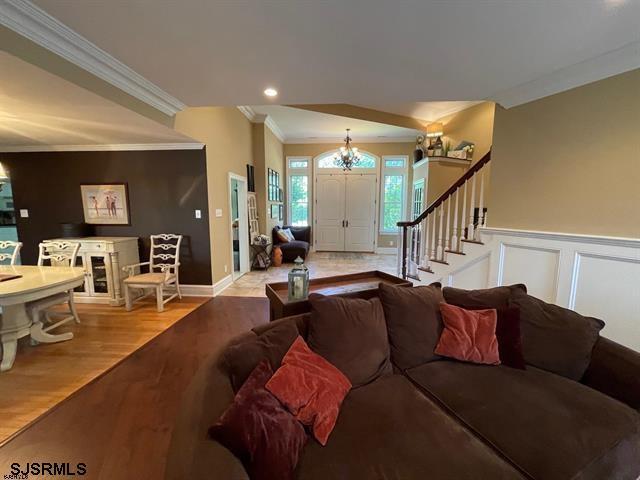 living room featuring a chandelier, light hardwood / wood-style flooring, and ornamental molding