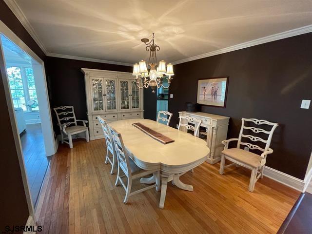 dining room featuring light wood-type flooring, a chandelier, and crown molding