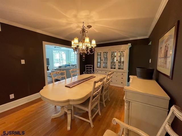 dining area with a chandelier, hardwood / wood-style floors, and crown molding