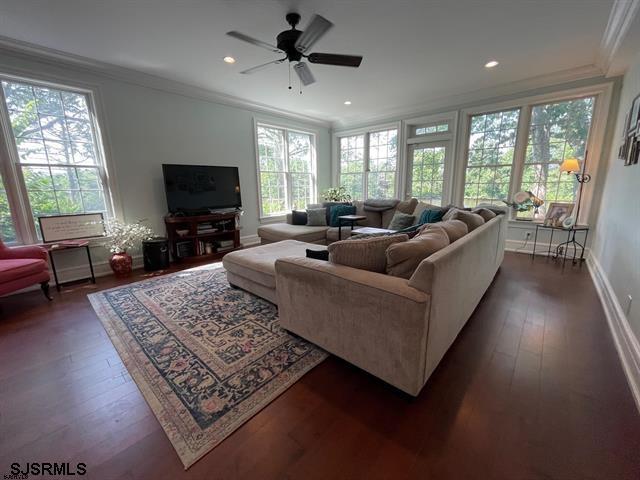 living room with ceiling fan, ornamental molding, and dark wood-type flooring