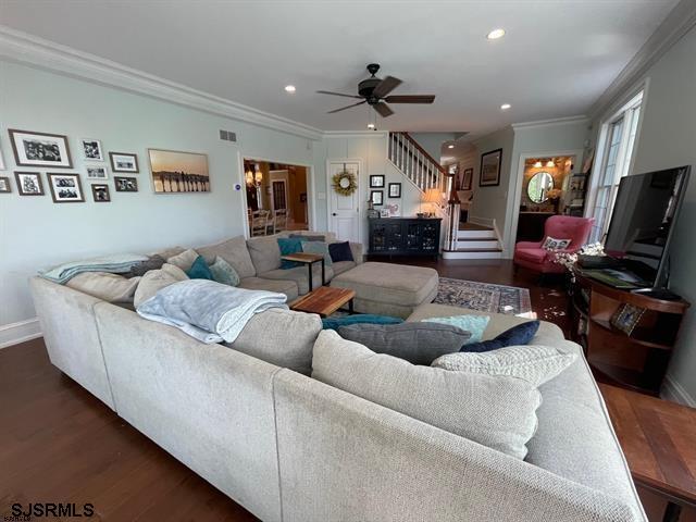 living room featuring ceiling fan, dark hardwood / wood-style floors, and crown molding