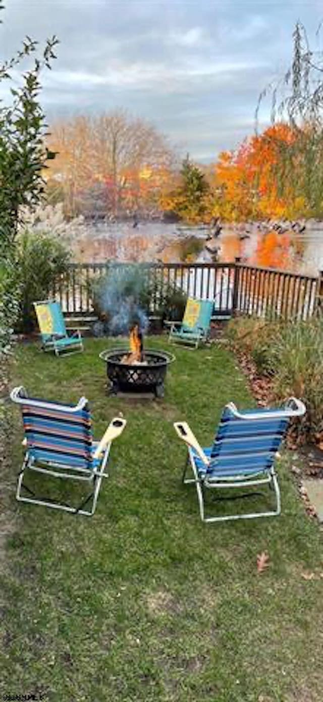 view of community with an outdoor fire pit and a lawn