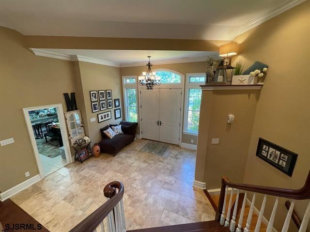 entryway with a chandelier and ornamental molding