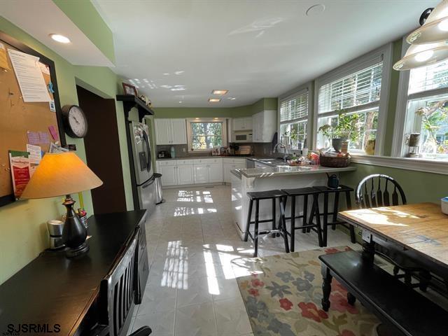 kitchen with sink, white cabinetry, a kitchen bar, and stainless steel fridge